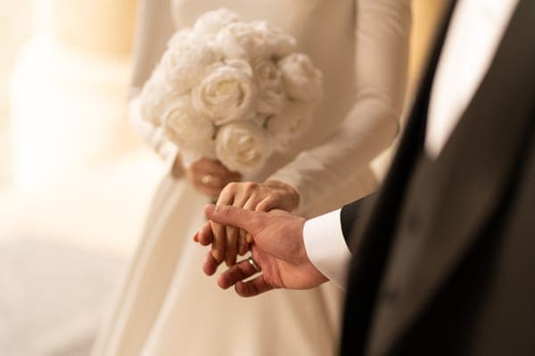 braut und Bräutigam geben sich einen eheversprechen ab und halten Hände mit einem weissen Rosenstrauss auf der hochzeit