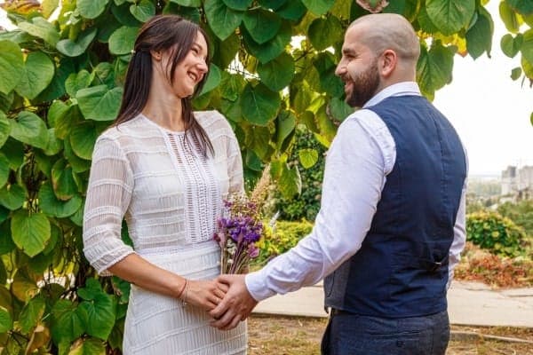 Braut und Bräutigam halten sich an den Händen und blicken sich verliebt an. Ein Symbol für Dankbarkeit am Ende einer Traumhochzeit.