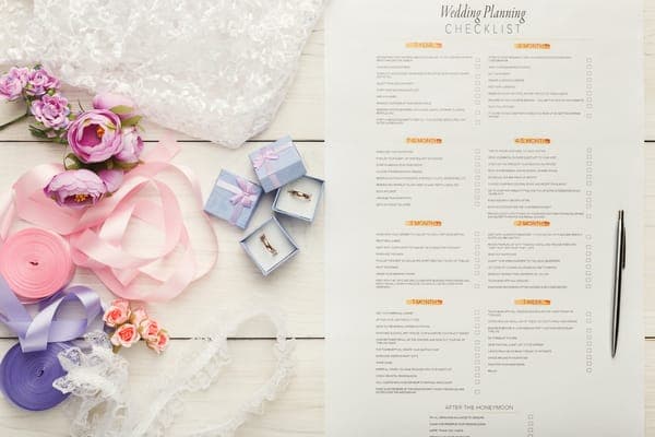 Detaillierte Hochzeitsplanungs-Checkliste mit Zeitplan, Eheringen und lila Blumendeko.