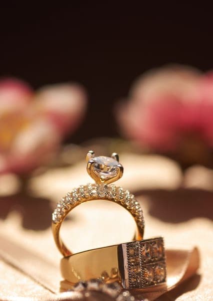 Goldener Verlobungsring mit Diamant und Pavé-Steinen auf warmem Hintergrund