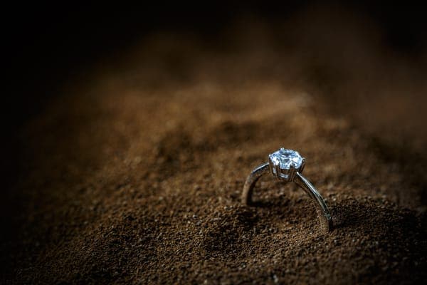 Ein kostbarer Damenring mit einem funkelnden Diamant im Sand