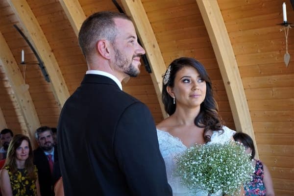 Brautpaar bei der Trauung in einer Holzkirche, Braut mit Schleierkraut-Bouquet