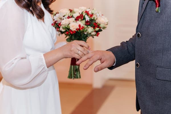 Hände mit Ringen Braut steckt während der Hochzeitszeremonie einen goldenen Ring an den Finger des Bräutigams und der Bräutigam das eheversprechen zum weinen vorträgt