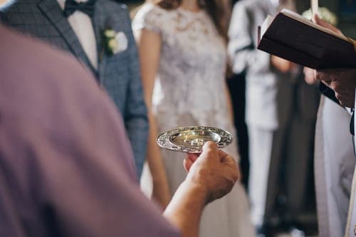 A close-up of a wedding ceremony in which a silver bowl is held