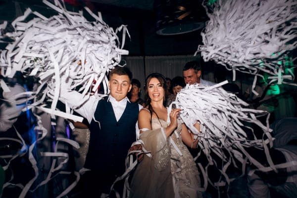 Braut und Gäste feiern auf der Tanzfläche und werfen weisse Papierstreifen in die Luft.