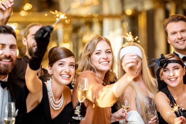 Friends in 1920s-style evening wear celebrating with sparklers and glasses of champagne