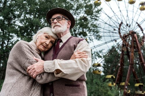 Ein älteres Ehepaar umarmt sich liebevoll im Freien, ein Sinnbild für die vielen gemeinsamen Jahre bis zur Steinernen Hochzeit.
