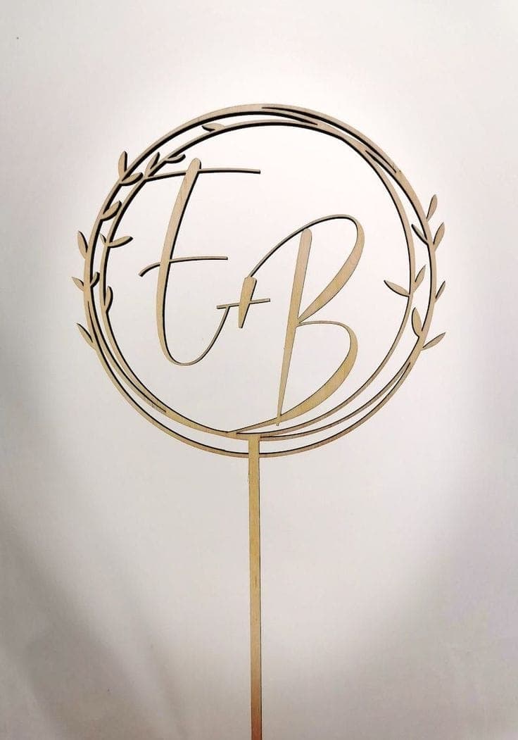 Ein moderner Cake Topper in Gold mit den verschlungenen Initialen des Paares, eine stilvolle Wahl für einen Hochzeit Cake.
