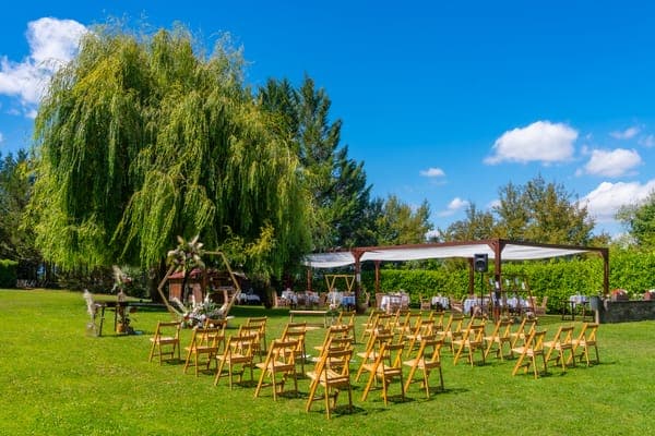 Eine idyllische Hochzeit Sitzordnung im Grünen, bei der goldene Stühle auf einer Wiese für die Gäste bereitstehen.