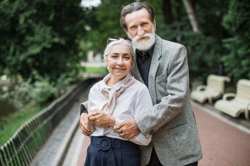 Glückliches älteres Paar lächelt in die Kamera und verkörpert die Freude und das Erreichte einer Ehe, die die Steinerne Hochzeit feiert.