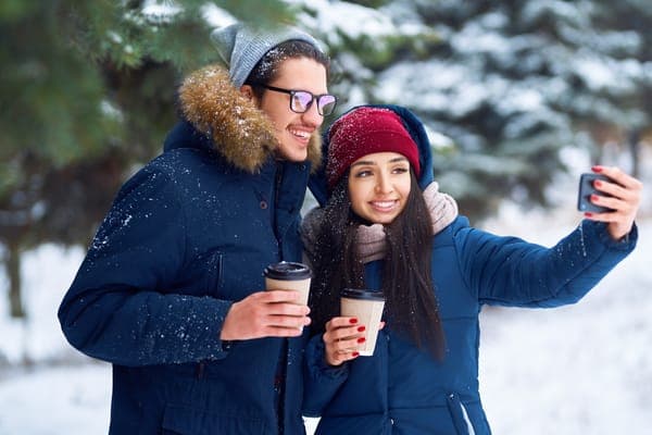 Winter Date Ideen: Paar beim Schneespaziergang mit Kaffee gemütliche Date Ideen Schweiz im Winter.