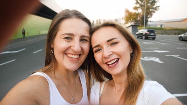 Zwei beste Freundinnen lächeln glücklich in die Kamera – ein perfekter Moment, um die Frage zu stellen: „Willst du meine Trauzeugin sein?“.