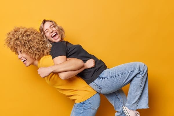Zwei Freundinnen albern herum und lachen ausgelassen, was die tiefe und fröhliche Freundschaft zeigt, die man mit der Frage „Willst du meine Trauzeugin sein?“ ehrt.