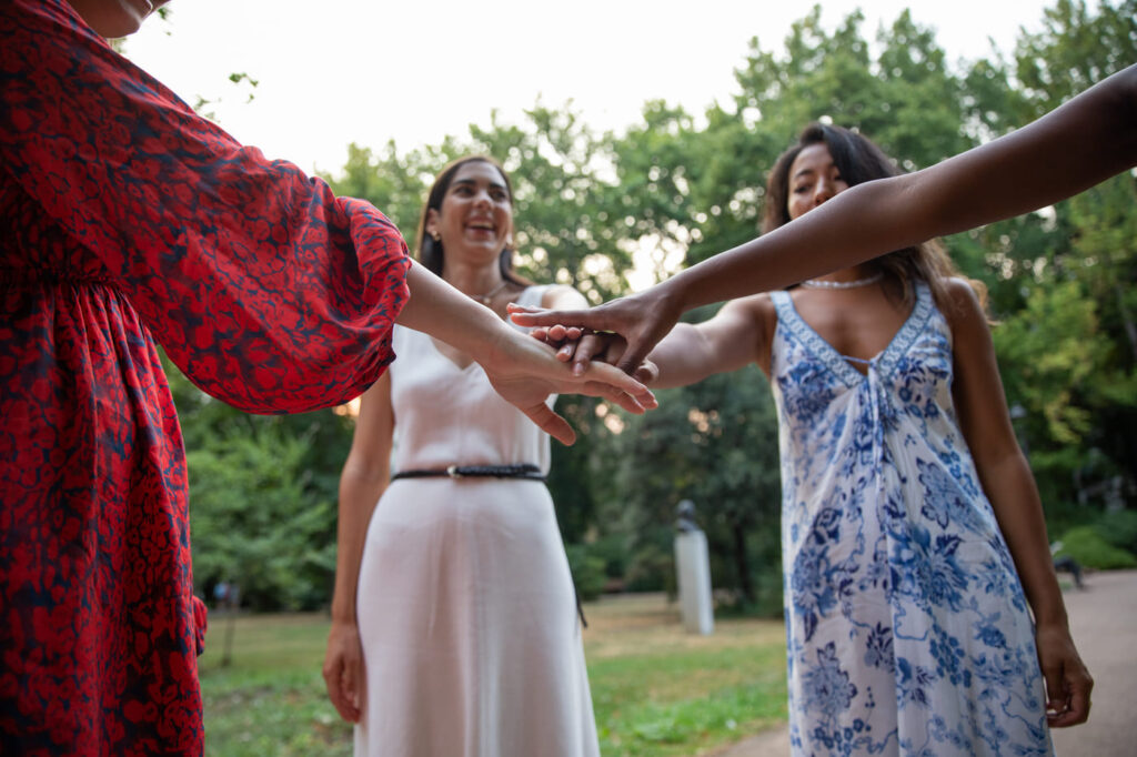 Hochzeitsspiele für Gäste: Kreative Ideen für Ihre Traumhochzeit Unterhaltung Hochzeit, Hochzeitsblog Vier weibliche Hochzeitsgäste legen ihre Hände im Kreis zusammen, symbolisch für Teamgeist bei Hochzeitsspielen für Gäste zum Kennenlernen.