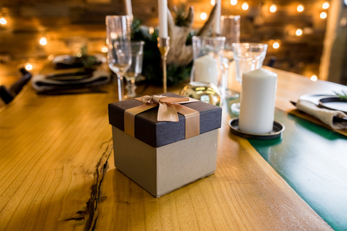 Gastgeschenke Hochzeit: Die schönsten Ideen für ein unvergessliches Dankeschön Hochzeitsgeschenke, Hochzeitsblog Stilvoll verpacktes Gastgeschenk zur Hochzeit mit goldener Schleife auf einem Holztisch als persönliches Dankeschön und Teil der Tischdeko