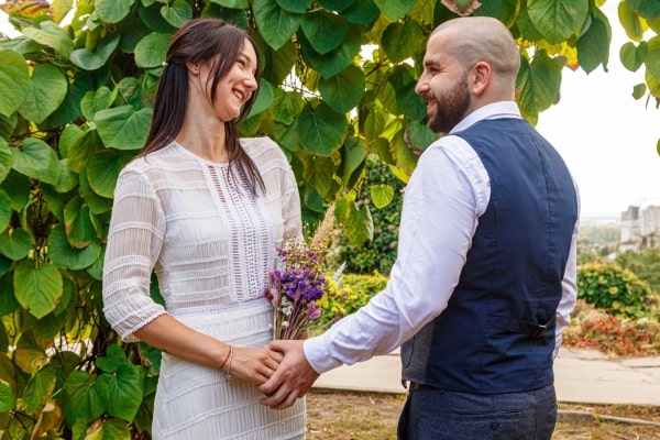 Gastgeschenke Hochzeit: Die schönsten Ideen für ein unvergessliches Dankeschön Hochzeitsgeschenke, Hochzeitsblog Braut und Bräutigam halten sich an den Händen und blicken sich verliebt an. Ein Symbol für Dankbarkeit am Ende einer Traumhochzeit.