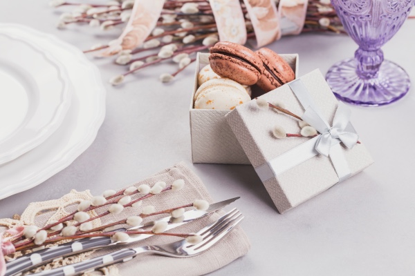 Kleine Geschenkbox mit Macarons als kulinarisches Gastgeschenk zur Hochzeit, liebevoll platziert auf einer festlich gedeckten Tafel.