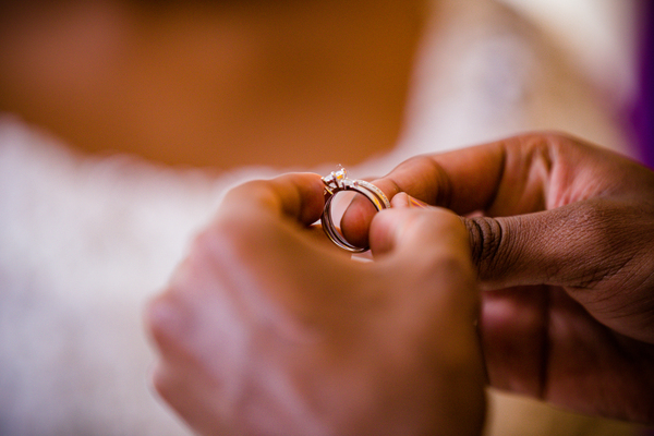 Wo trägt man den Ehering in der Schweiz: Tradition, Regeln & moderne Trends Unterhaltung Hochzeit, Hochzeitsblog Hände halten vorsichtig einen funkelnden Diamant Verlobungsring vor dem unscharfen Hintergrund eines weissen Brautkleides.