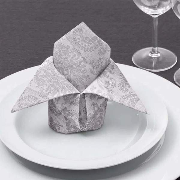 Servietten falten Hochzeit: Der ultimative Guide mit 11 zauberhaften Faltanleitungen DIY Hochzeit, Hochzeitsblog Gemusterte graue Serviette kunstvoll gefaltet auf weissem Teller, daneben Weinglas