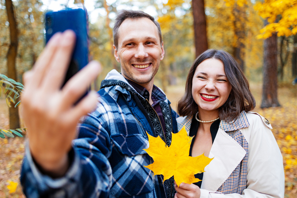 Date Ideen im Herbst - dein umfassender Guide für romantische & aktive Momente in der Schweiz Paare, Hochzeitsblog Date-Ideen Herbst: Selfie eines Paares mit gelbem Ahornblatt im herbstlichen Park.