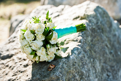 Ein Hochzeitsstrauss mit weissen Rosen liegt auf einem grossen Stein, Symbol für die Beständigkeit der Ehe bei der Steinernen Hochzeit.
